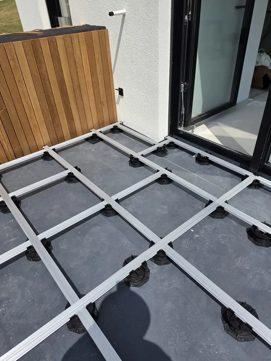 First paver dropped into the grid at the corner by the glazing at a Slovenia mansion rooftop