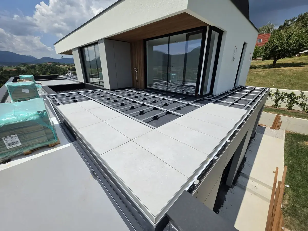 First course of large porcelain slabs bedded on pedestals at a Slovenia mansion rooftop with alpine view
