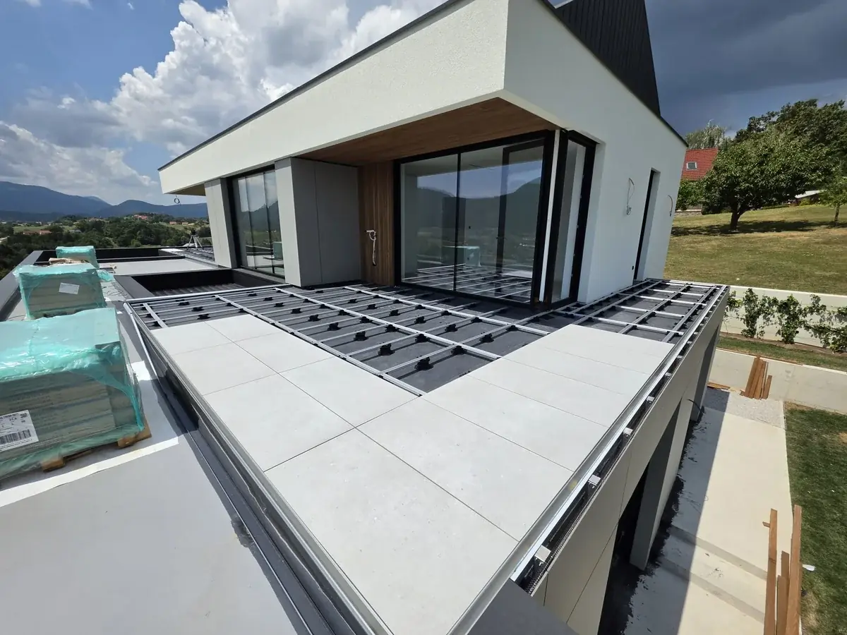 Installer aligning pedestal heights near the timber screen at a Slovenia mansion rooftop